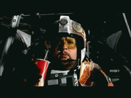Star Wars gif. William Hootkins as Starfighter Pilot Jek Porkins Red Six, in his cockpit and modified to have food and soda in his hands, talks to Garrick Hagon as Starfighter Pilot Biggs Darklighter Red Three, laser blasts flying through space, until he's hit and goes down, snacks in hand.