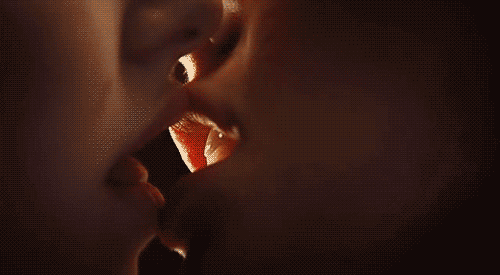 Video gif. A zoomed-in shot of two people french kissing.