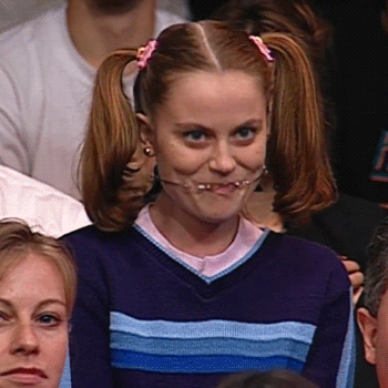 Celebrity gif. Amy Poehler in character during a bit on the Conan O'Brien Show. She's wearing her hair in pigtails and has a headgear that's fully on display stretching across her wide smiling open mouth. She's bubbling over in excitement and waving at the audience members around her.
