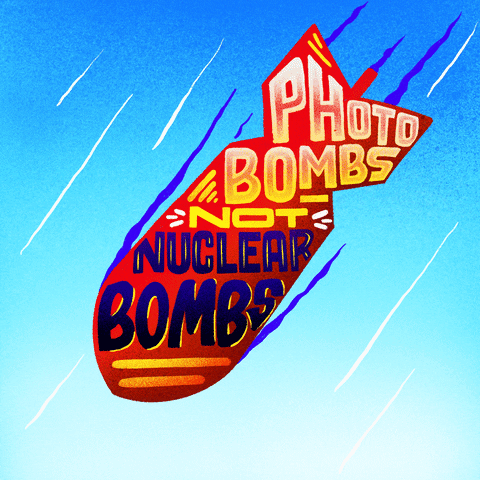 Digital art gif. Cartoon nuclear bomb hurtles toward the ground against a bright blue sky. Colorful, all-caps text inside the bomb reads, "Photobombs, not nuclear bombs."