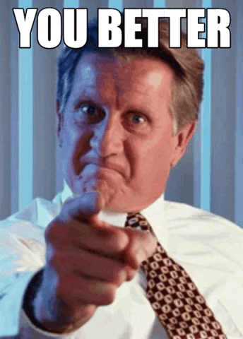 Video gif. A man with a fierce face points a firm and shaking finger directly at us. 