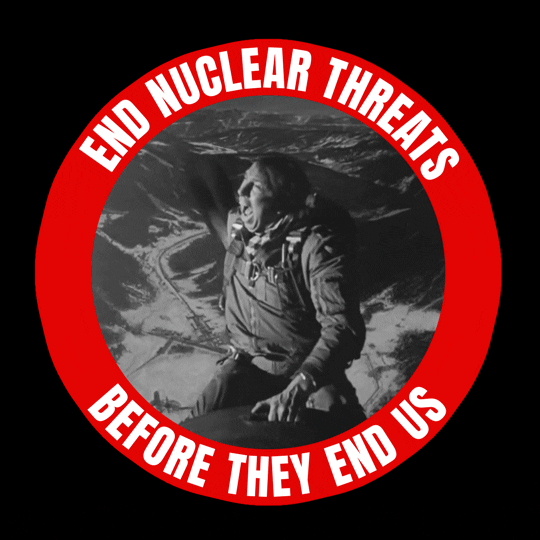 Digital art gif. Red circle with a slash through it superimposed over a black and white video clip of a man wearing a military uniform riding a nuclear warhead toward the ground, eventually exploding in a flash of light. Inside the red circle, text reads, "End nuclear threats before they end us."