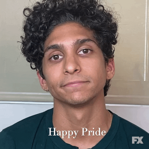 Celebrity gif. Angel Bismark Curiel looks at us and smiles as he says, “Happy pride.”