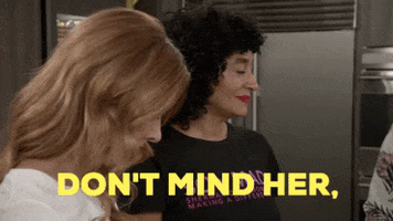 TV gif. Tracee Ellis Ross as Rainbow Johnson from Blackish speaks casually to a woman in the foreground while motioning with her head to someone offscreen. Text, "Don't mind her. She's old."