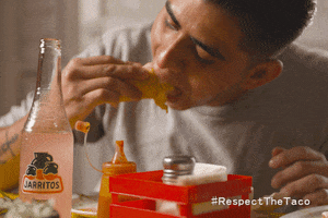 Ad gif. Boy enjoys a bite of a taco at a table set with condiments and a pink Jarritos soda bottle. Text at the bottom right reads, "Hashtag Respect The Taco."