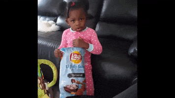 Video gif. Little girl holds a large bag of Lay's potato chips and appears annoyed, rolling her eyes and then looking to the side.