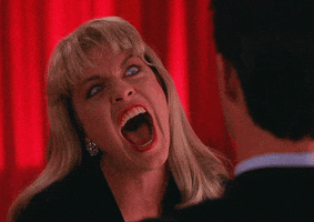 Movie gif. Sheryl Lee as Laura in Twin Peaks. She looks possessed as she makes a biting face at someone, staring at them with crazed eyes and an open mouth, similar to a vampire.