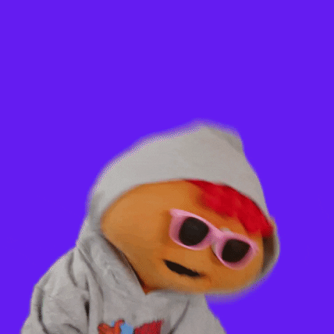 Video gif. Gilbert puppet dressed in a grey hoodie and pink sunglasses, hops around, dancing while the background cycles through a rainbow of colors.