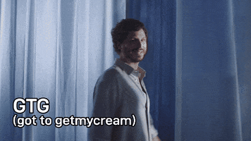 Sponsored gif. Michael Cera is wearing a silky, breezy light blue button up and he has a serene smile on his face while he spins through a room filled with the same colored soft fabric that drapes down from the ceiling. Text, "GTG - Got to getmycream." 