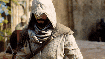 Video game gif. Basim in "Assassin's Creed Mirage" walks towards us with a badass expression on his face, hood pulled down over his eyes as other characters move about a medieval city in the blurred background. 