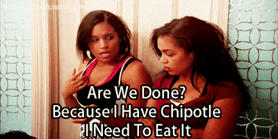 Video gif. Two girls who have messy hair stand next to each other. One girl looks down with a tired expression and has her arms crossed. The other girl looks around and says, ‘Are we done? Because I have Chipotle I need to eat it.”