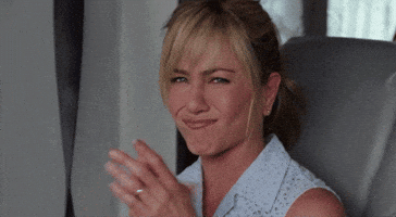 Celebrity gif. Jennifer Aniston has a tight smile on her face while she claps. 