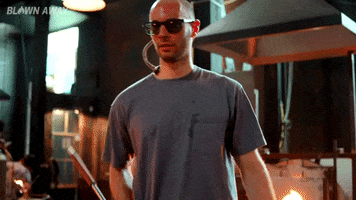 TV gif. Man wearing a T-shirt and sunglasses, in a glassblowing studio on Blown Away, walks past us and glances as he says "Let's do it!" which appears as text.