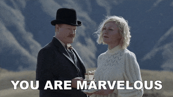 Movie gif. Jesse Plemons and Kirsten Dunst as George Burbank and Rose Gordon in The Power of the Dog stand amidst a ruralscape while holding cups of tea. Gordon's hair blows softly in the breeze as Burbank gazes at her fondly and says, "You are marvelous," which appears as text.