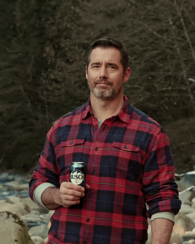 Video gif. A man wearing a red flannel holding a Busch beer holds up his pointer finger and shakes it around as if to say “no way.”