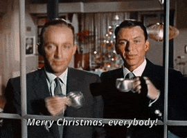 Movie gif. Bing Crosby and Frank Sinatra in Happy Holidays with Bing and Frank look out a window holding two small metal cups. They clink the cups and say, “Merry Christmas, everybody!” and they both take sips.