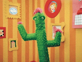 Video gif. Green cactus puppet waves out his arms with a friendly look saying, "Good morning, friend!'