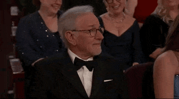 Oscars 2024 GIF. Steven Spielberg sits in the audience and stares at the stage as he nods slowly but significantly, nodding his head three times in a row. 
