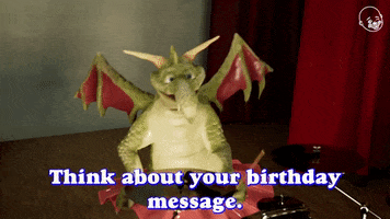 Video gif. A dragon puppet wearing a tutu from the Eternal Family Animatronic Band plays a drum set. Text: "Think about your birthday message. Think about Your special package! Go."