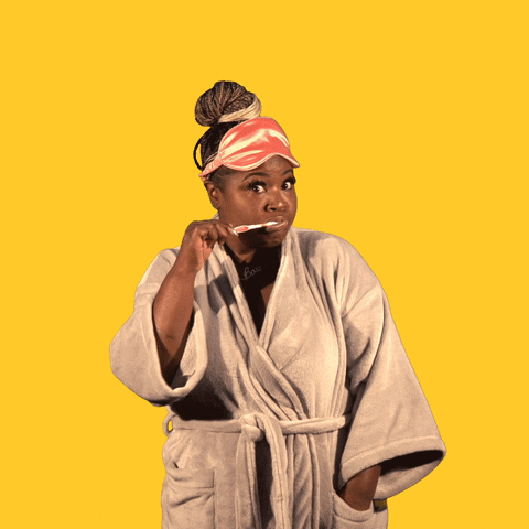 Video gif. Woman in a robe holds a toothbrush in her hand and brushes with a smile, pulling the toothbrush away to say, "Good morning" with upbeat enthusiasm against a golden yellow background.