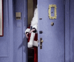 Friends gif. An excited Matthew Perry as Chandler walks in the room dressed as Santa, and says, “Merry Christmas!”