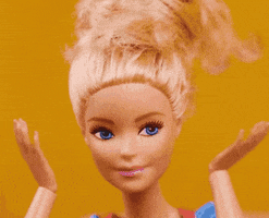 Video gif. A closeup on a Barbie doll with its hair up as its hands move to its mouth in "surprise".
