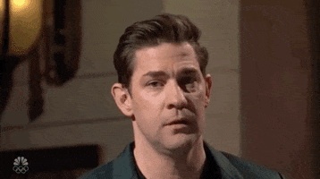 SNL gif. John Krasinski tips his head to the side as he shrugs with a quirked half smile.