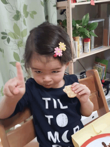 Video gif. A little girl snacks on a cookie as she glares up at us and wags a finger as if saying no way.
