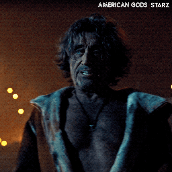 TV gif. Ian McShane as Mr. Wednesday. He's standing next to a busy street, with drunken eyes, and roars before whipping open his coat to reveal his naked body to the cars passing by. 