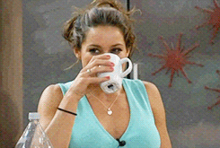 Video gif. A woman taking a sip of water accidentally spits it out when she begins to laugh.