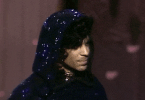 Celebrity gif. Prince wears a sparkly hood and turns his back to us.