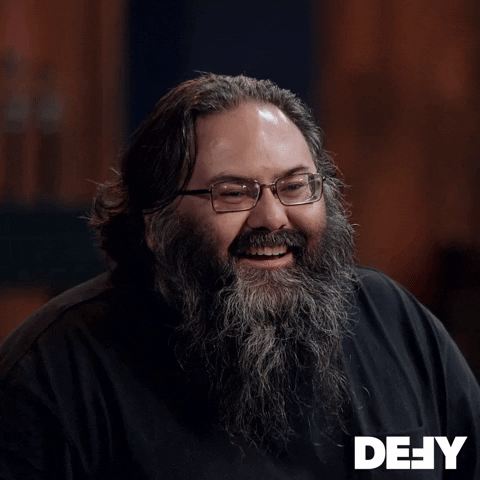 Reality TV gif. Talking head of a bearded Forged in Fire contestant with a giddy smile saying, "Aw yeah!"