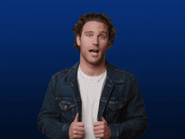 Video gif. Aaron Taos, a musical artist, looks sideways at us before cheekily putting his hands to his lips and saying, "Oops."