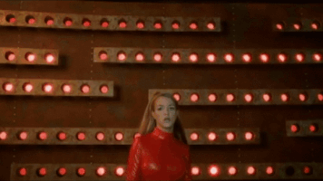 Music video gif. Britney Spears in Oops I Did It Again, wears a red bodysuit and walks aggressively towards us, reaching out and grabbing right at our face. Then we see her face in close up as she sings, "Oops I did it again."