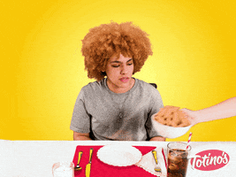 Video gif. A woman waits eagerly as a hand delivers a bowl of steaming pizza rolls and sets them in front of her. Her eyes bulge comically as she holds up a fork and knife. 
