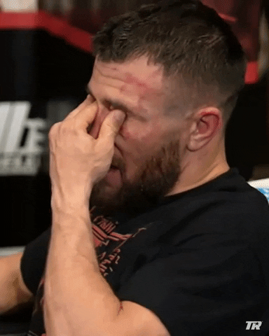 Video gif. Vasyl Lomachenko covers his face with his hands, squeezing his eyes with his fingers as he begins to sob.