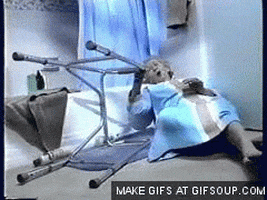 Video gif. Elderly woman who has fallen cries for help as she clutches onto her walker, which has fallen next to her.