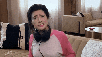 Celebrity gif. Sarah Silverman sits at home in a lazy pink and white fit with her hair tied into a messy ponytail and black headphones wrapped around her neck. She appears to be taken aback and baffled by something.