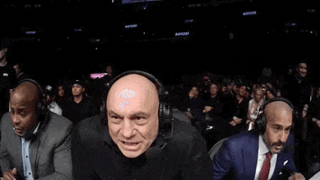 Sports gif. Joe Rogan, Daniel Cormier, and Jon Anik are calling a UFC fight and all three of their jaws drop as they jump back and look in total shock and awe.