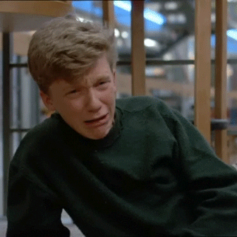 Movie gif. Anthony Michael Hall as Brian in The Breakfast Club lies propped up on one elbow, bawling, deeply hurt, burying his face in the sleeve of his sweatshirt to hide his tears. 