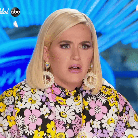 Video gif. Singer Katy Perry stares blankly, blinking slowly at an off-camera contestant during an episode of America's Got Talent.