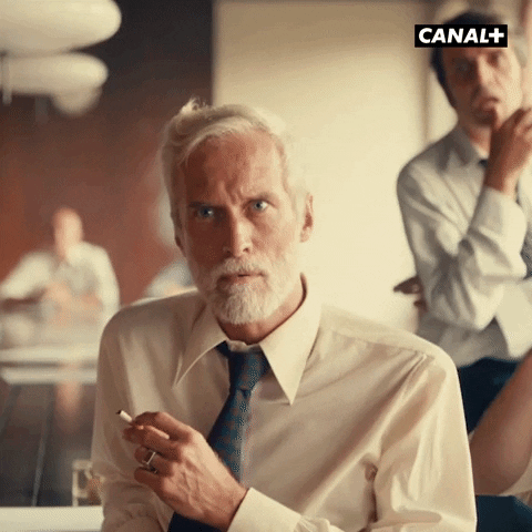 Video gif. A man looks stunned but he quickly puts his cigarette in his mouth so his hands can be free to clap enthusiastically.