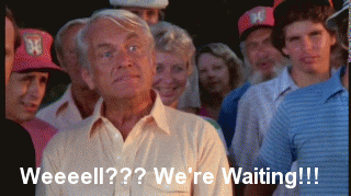 Movie gif. Ted Knight as Judge Elihu Smails in Caddyshack, stands in a yellow polo shirt in a group of people. The elderly white man eyes grow wide. He shakes his head and leans his head forward with an exaggerated, open mouth. Text reads, "Weeeell???We're Waiting!!!"