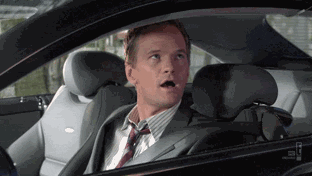 TV gif. Neil Patrick Harris as Barney Stinson from How I Met Your Mother breaks the fourth wall by staring straight at us from the driver's seat and giving us two thumbs up while grinning widely.