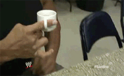 Sports gif. A bulky pro wrestler backstage drinking from a teacup that he wears like a ring on his finger.
