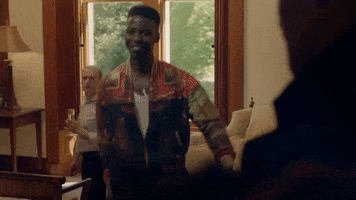 TV gif. Jyuddah Jaymes as Aubrey in Clique. He has a wide and sheepish grin as he walks towards a friend and he raises his arms and shrugs his shoulders as he walks.