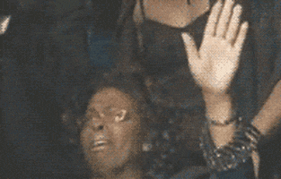Video gif. A woman holds her hands up in grateful prayer, with happy tears in her eyes.