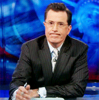 TV gif. Stephen Colbert on Late Night taps a pen on his desk as he smirks, waiting impatiently. 