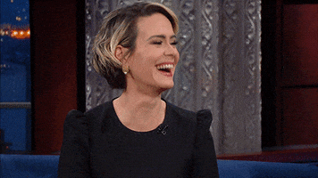 Celebrity gif. Sarah Paulson on The Late Show with Stephen Colbert laughs hysterically. She points at Steven and claps. 