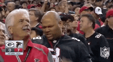 Sports gif. Man wearing an Atlanta Falcons jersey stands in a crowd of fans and thrusts his arms in the air as he leans back with a pained expression on his face.